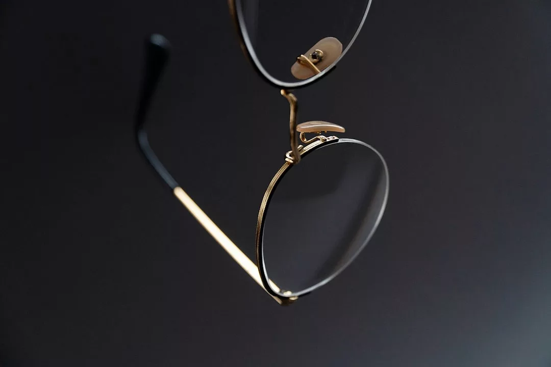 Nahaufnahme einer goldfarbenen GLAMESiA-Brille mit schwarzen Bügeln vor einem dunklen Hintergrund.