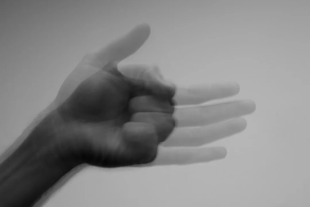 Ein unscharfes Schwarz-Weiß-Foto zeigt eine Hand in Bewegung, mit sich überlappenden Bildern der sich ausstreckenden und schließenden Finger vor einem schlichten Hintergrund - ein fesselndes Bild, das den dynamischen Geist von GLAMESiA verkörpert.