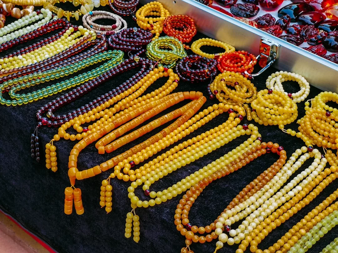 GLAMESiA Perlenketten und Armbänder in verschiedenen Farben werden auf einem schwarzen Tuch an einem Marktstand ausgestellt.