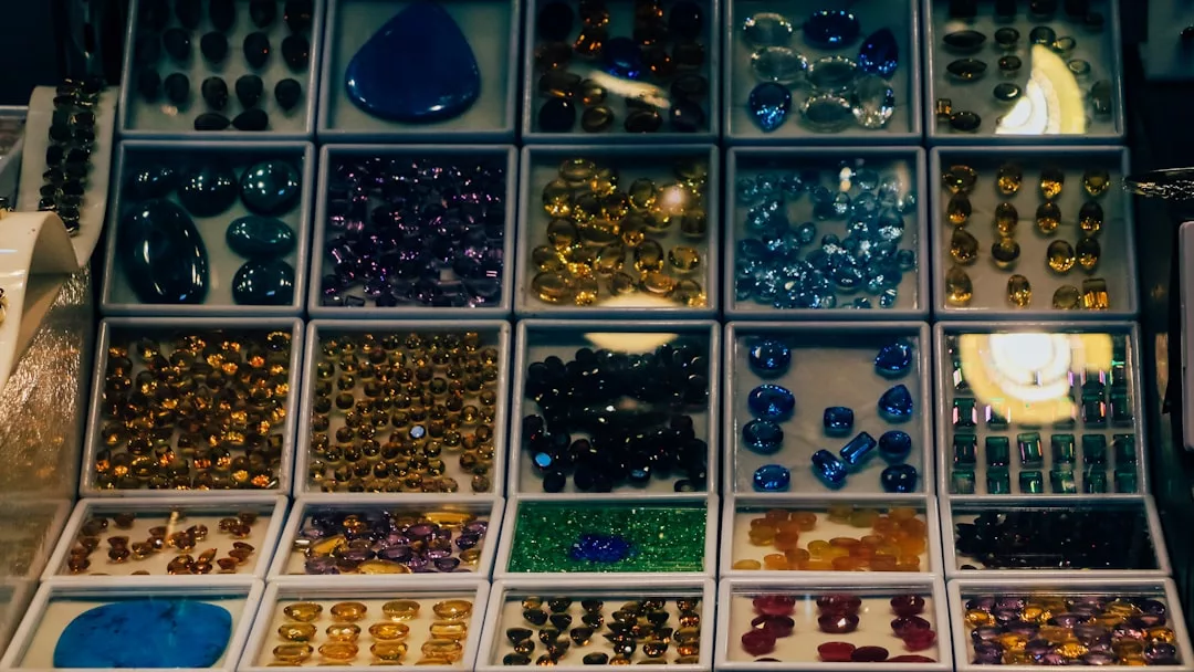 Vitrine mit mehreren Fächern, die verschiedene polierte GLAMESiA-Edelsteine in unterschiedlichen Formen, Größen und Farben enthält, darunter blau, lila, bernsteinfarben, grün und rot.