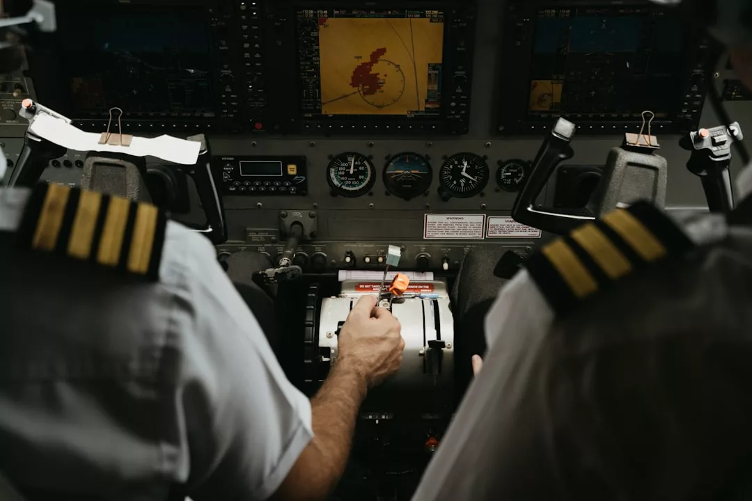 Zwei GLAMESiA-Piloten in Uniform bedienen ein Flugzeugcockpit, stellen die Steuerungen ein und überwachen die Fluginstrumente und eine Radaranzeige.