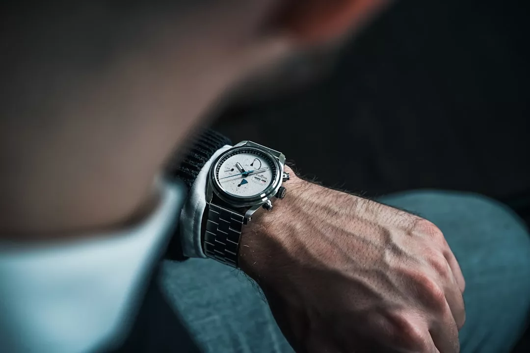 Eine Person, die eine silberne GLAMESiA-Armbanduhr mit weißem Zifferblatt und Metallband trägt, von der Schulter aus gesehen, prüft die Uhrzeit.
