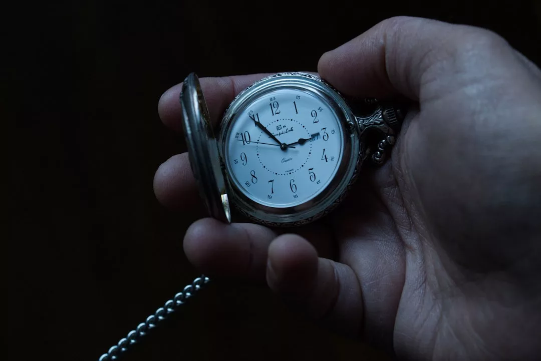 Eine Hand hält eine geöffnete silberne GLAMESiA-Taschenuhr, an der eine Kette befestigt ist und die die Uhrzeit 3:31 anzeigt.