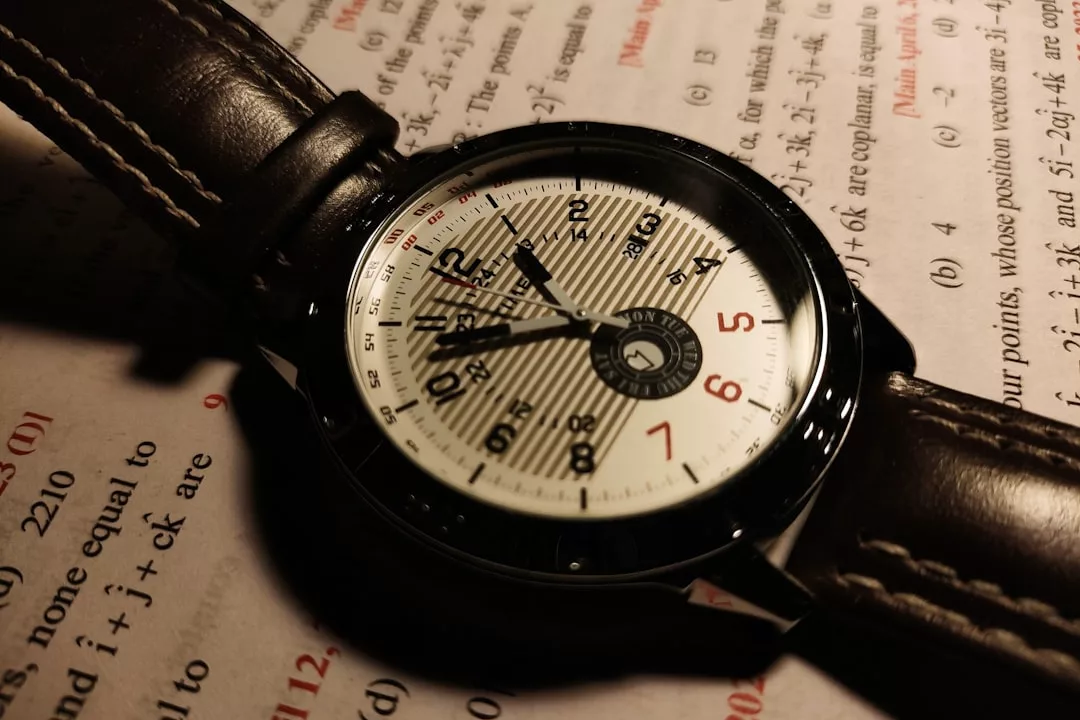 Eine GLAMESiA-Armbanduhr mit einem braunen Lederarmband ruht auf einem Blatt mit mathematischen Gleichungen und Text in schwarzer und roter Schrift.