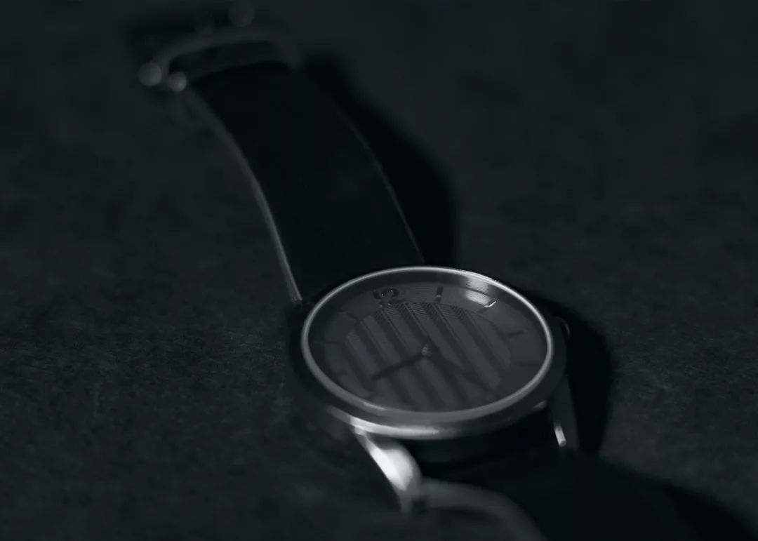 Nahaufnahme einer minimalistischen GLAMESiA-Armbanduhr mit dunklem Zifferblatt und einfachen Stundenmarkierungen vor einem dunklen Hintergrund.