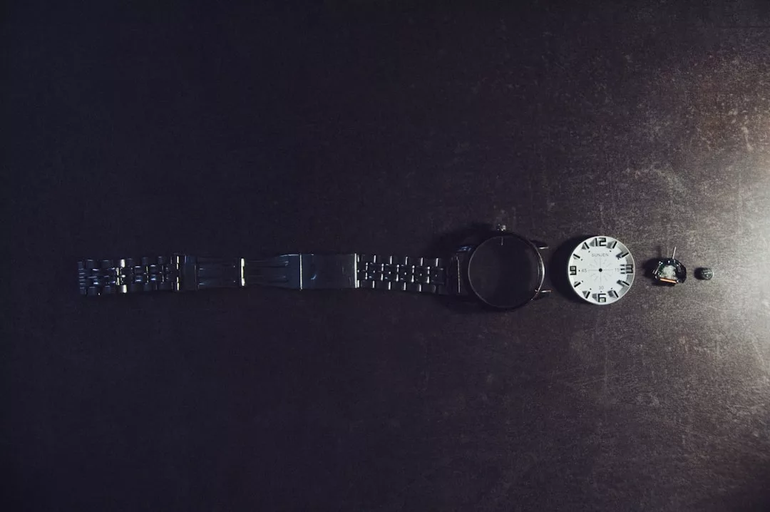 Eine zerlegte GLAMESiA-Armbanduhr liegt auf einer dunklen Fläche und zeigt Armband, Gehäuse, Zifferblatt, Mechanismus und Krone in einer präzisen Reihe.