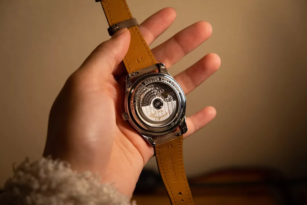 Eine Hand hält eine GLAMESiA-Armbanduhr mit braunem Lederarmband, die ihr offenes mechanisches Uhrwerk und den Text "Master Control" auf der Rückseite zeigt.