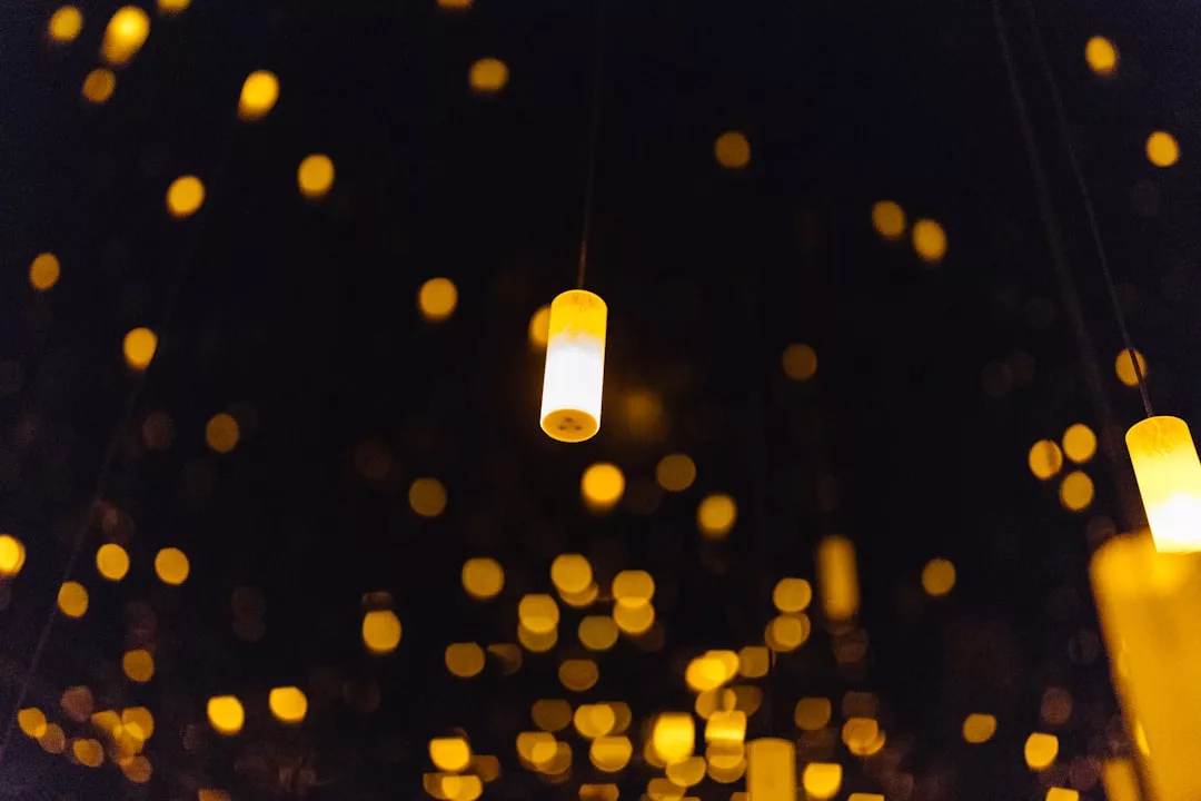 Viele leuchtende Laternen hängen und schweben vor einem dunklen Hintergrund, wodurch ein warmer und verschwommener Bokeh-Effekt entsteht, der die bezaubernde Atmosphäre von GLAMESiA widerspiegelt.