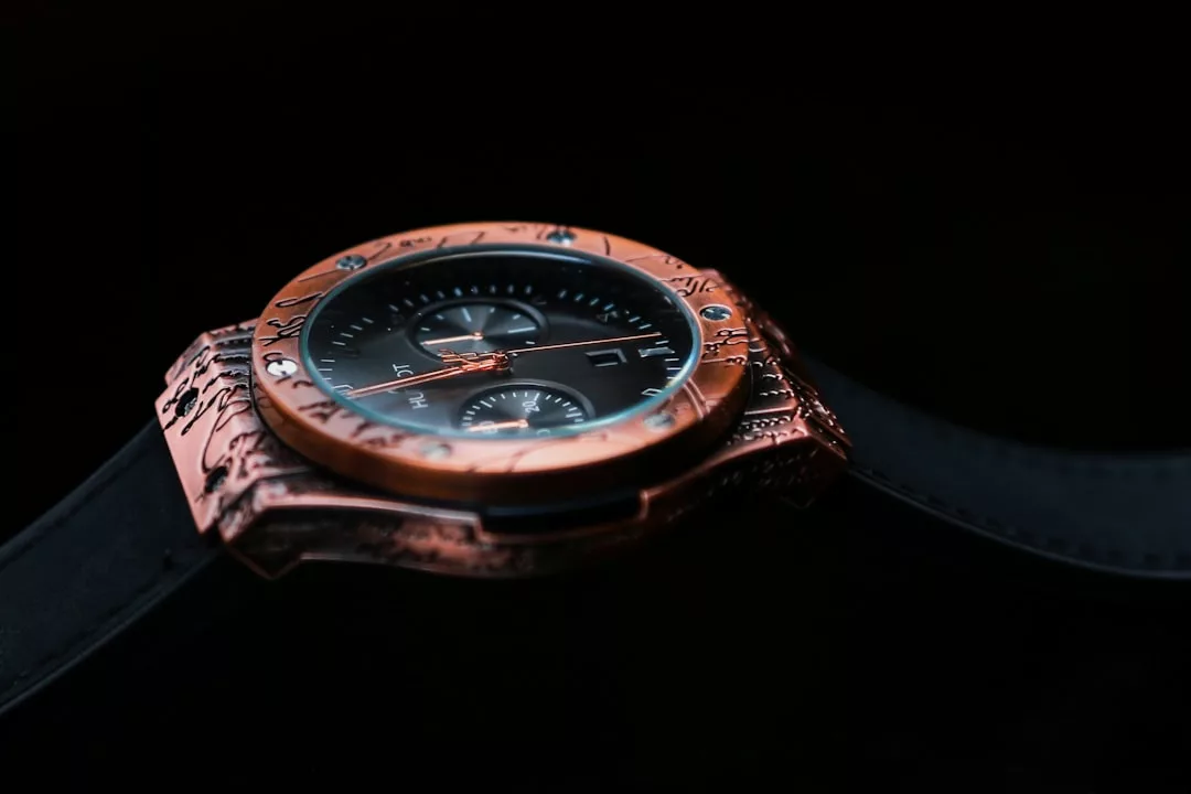 Nahaufnahme einer GLAMESiA-Armbanduhr mit gravierter Metalllünette, schwarzem Zifferblatt und zwei Hilfszifferblättern vor einem dunklen Hintergrund.