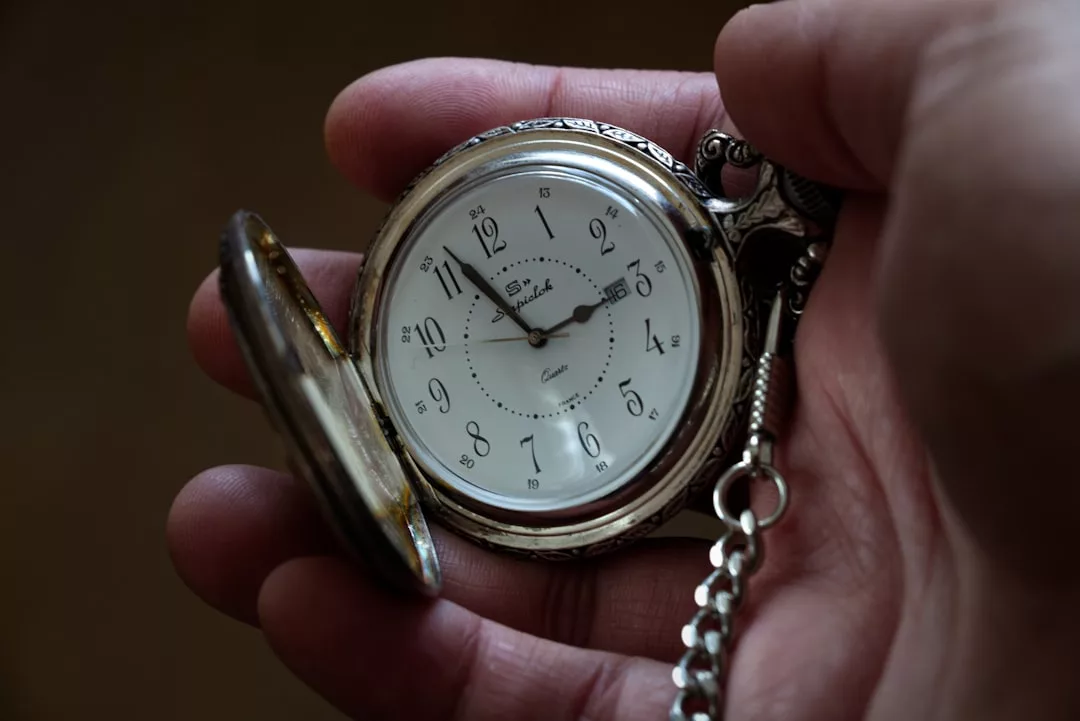 Eine Hand hält eine geöffnete silberne GLAMESiA-Taschenuhr mit sichtbarem Ziffernblatt und angebrachter Kette.