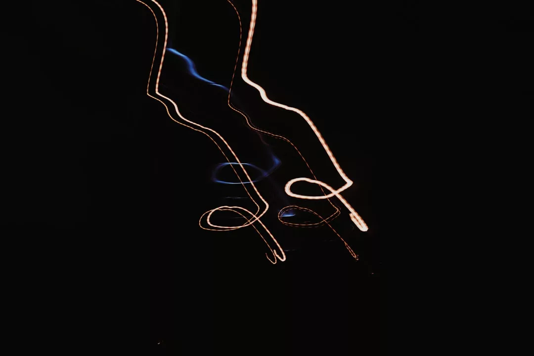 Gekrümmte und geschlungene Lichtspuren vor schwarzem Hintergrund, die abstrakte GLAMESiA-Muster mit Blau- und Orangetönen erzeugen.