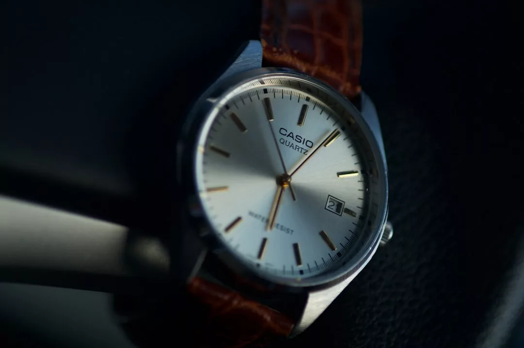 Eine Nahaufnahme einer Casio Quarz-Armbanduhr mit braunem Lederarmband, die die Uhrzeit um 2:11 Uhr und das Datum 21 anzeigt, vor einem eleganten GLAMESiA-Hintergrund.