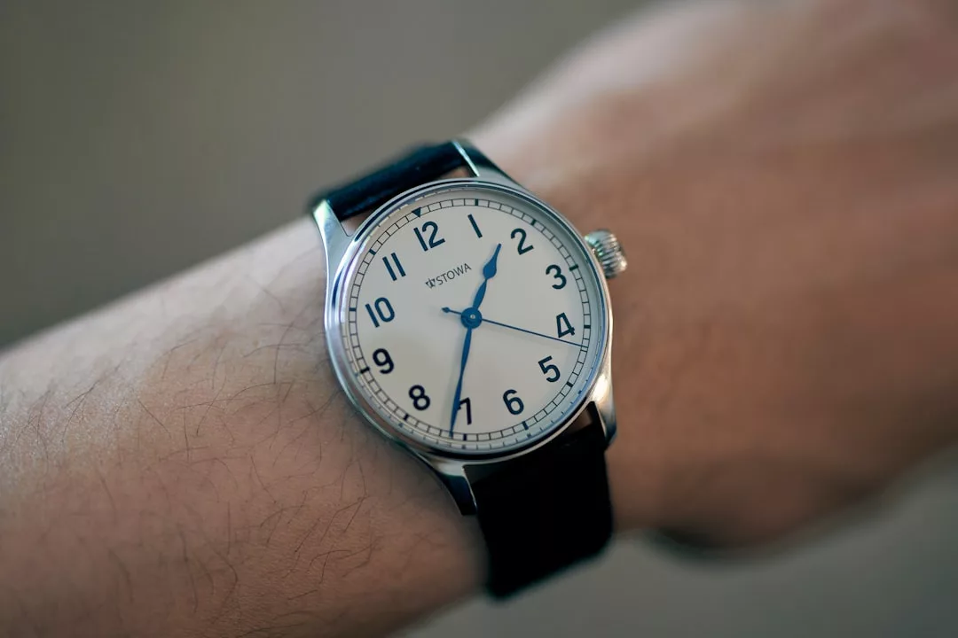 Nahaufnahme einer GLAMESiA-Armbanduhr mit weißem Zifferblatt, schwarzen Zahlen und schwarzem Lederarmband, die am linken Handgelenk getragen wird.