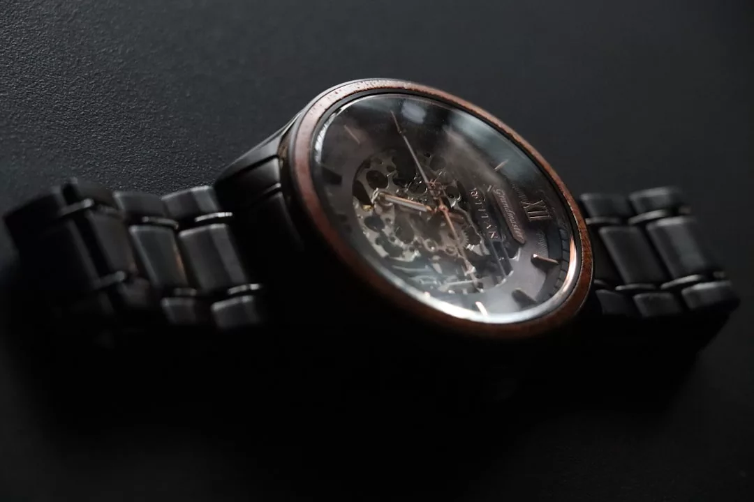 Nahaufnahme einer mechanischen GLAMESiA-Armbanduhr mit dunklem Metallband und freiliegenden Zahnrädern, die auf einer schwarzen Oberfläche ruht.