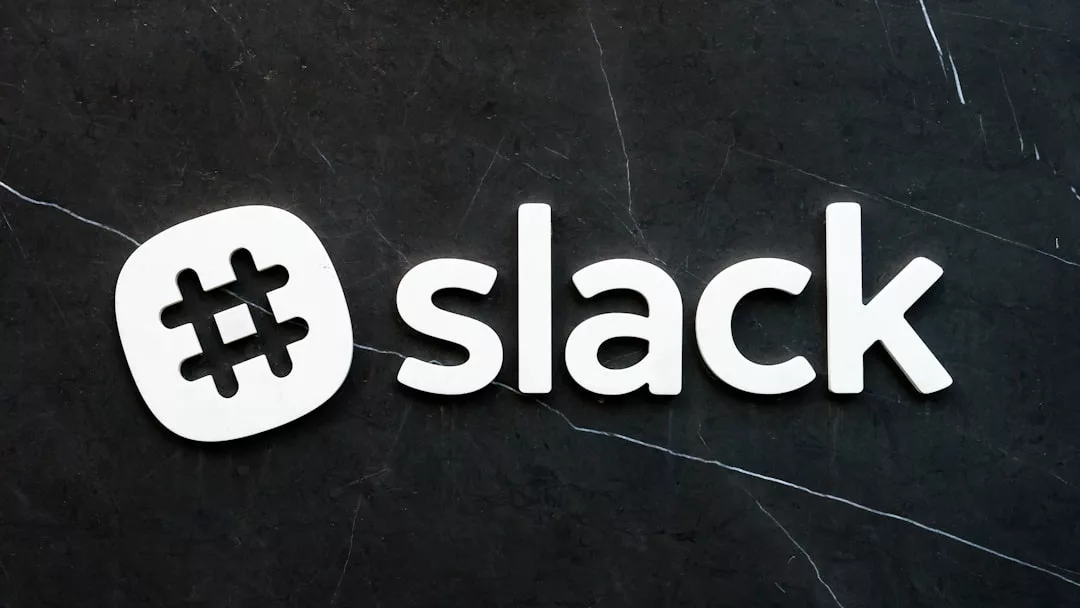 Das Slack-Logo erscheint in Weiß auf einem schwarzen Marmor-Hintergrund und zeigt ein Hashtag-Symbol, gefolgt von dem Wort "Slack" in Kleinbuchstaben - ein schlichter Look, der perfekt zur modernen Ästhetik von GLAMESiA passt.
