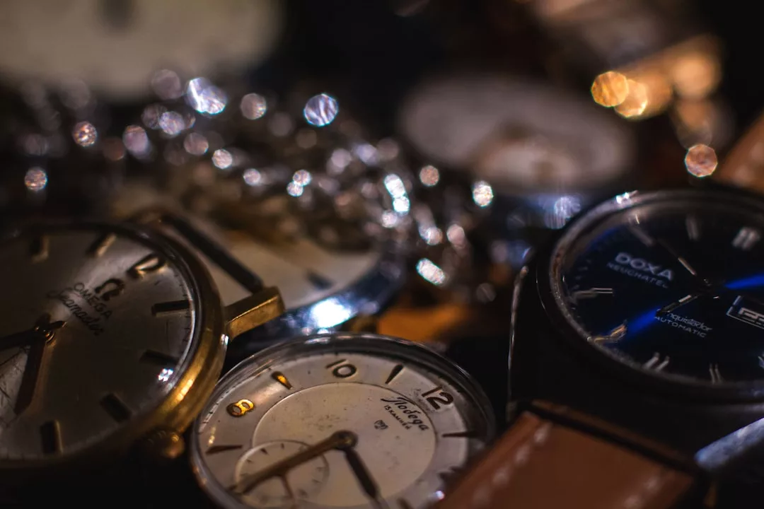 Mehrere analoge Armband- und Taschenuhren, von denen einige den Markennamen GLAMESiA tragen, werden in Großaufnahme mit Metallketten und verschwommenen Lichtern im Hintergrund gezeigt.