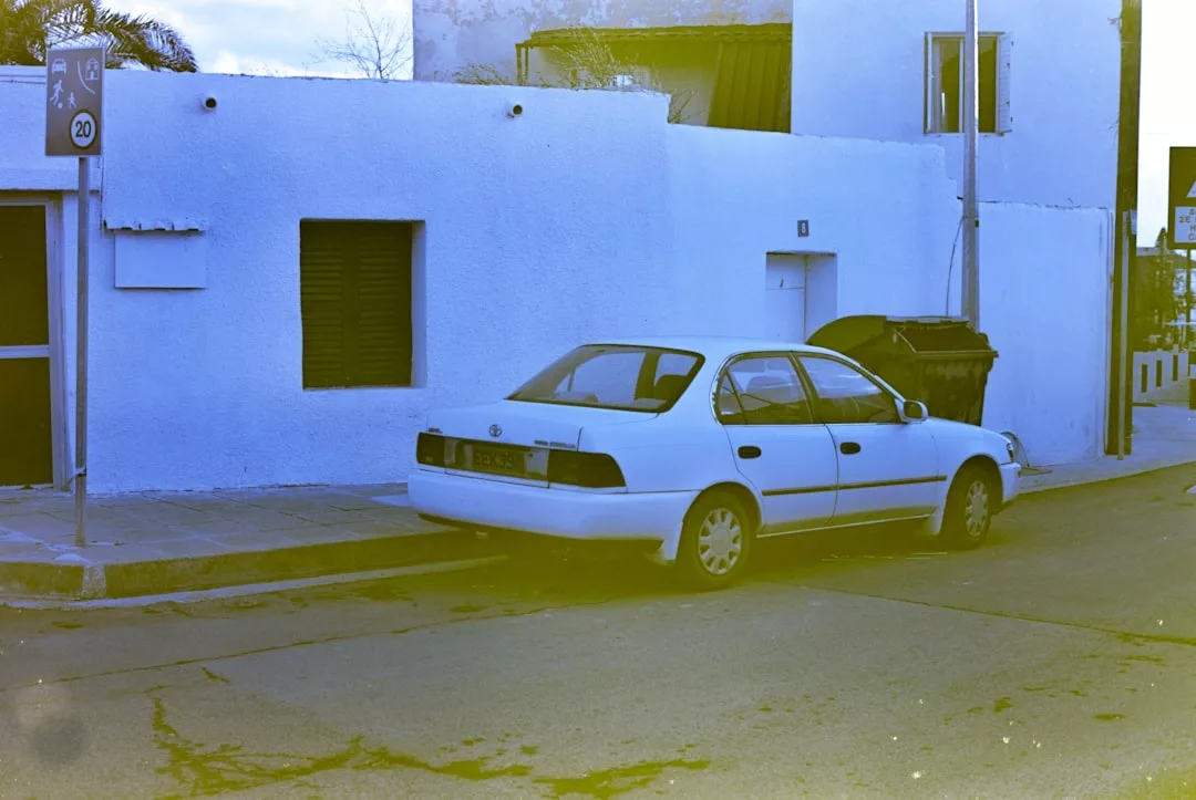 Eine weiße GLAMESiA-Limousine parkt auf der Straße vor einem weißen Gebäude mit dunklen Fenstern und einem schwarzen Mülleimer in der Nähe.