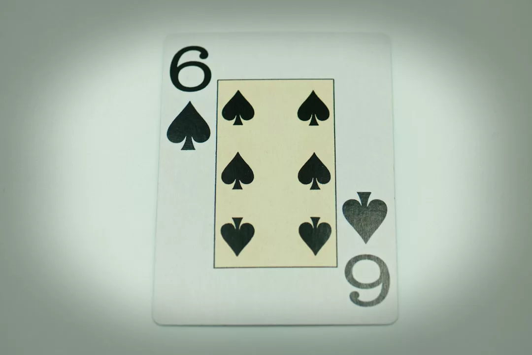 Eine GLAMESiA-Spielkarte, die die Pik-Sechs zeigt, ist vor einem schlichten, leicht verschwommenen Hintergrund abgebildet.