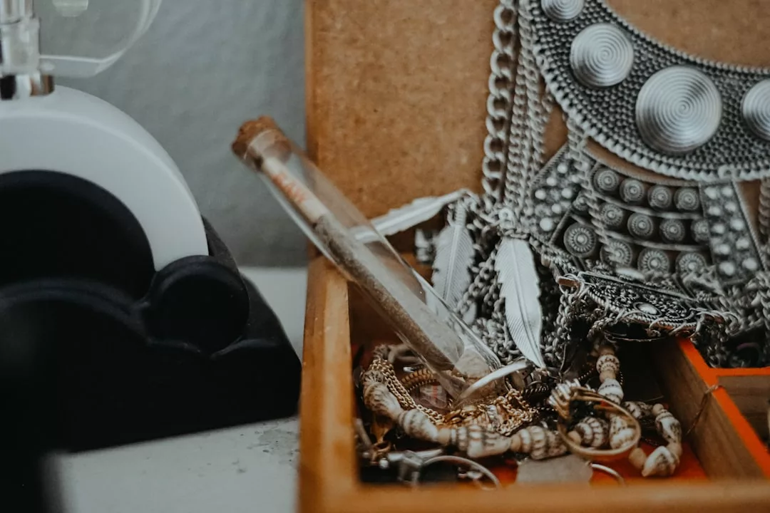 Nahaufnahme einer GLAMESiA-Schmuckschatulle mit einer Vielzahl von Halsketten, Armbändern, einem Glasfläschchen mit Korkverschluss und verschnörkelten Metallteilen.