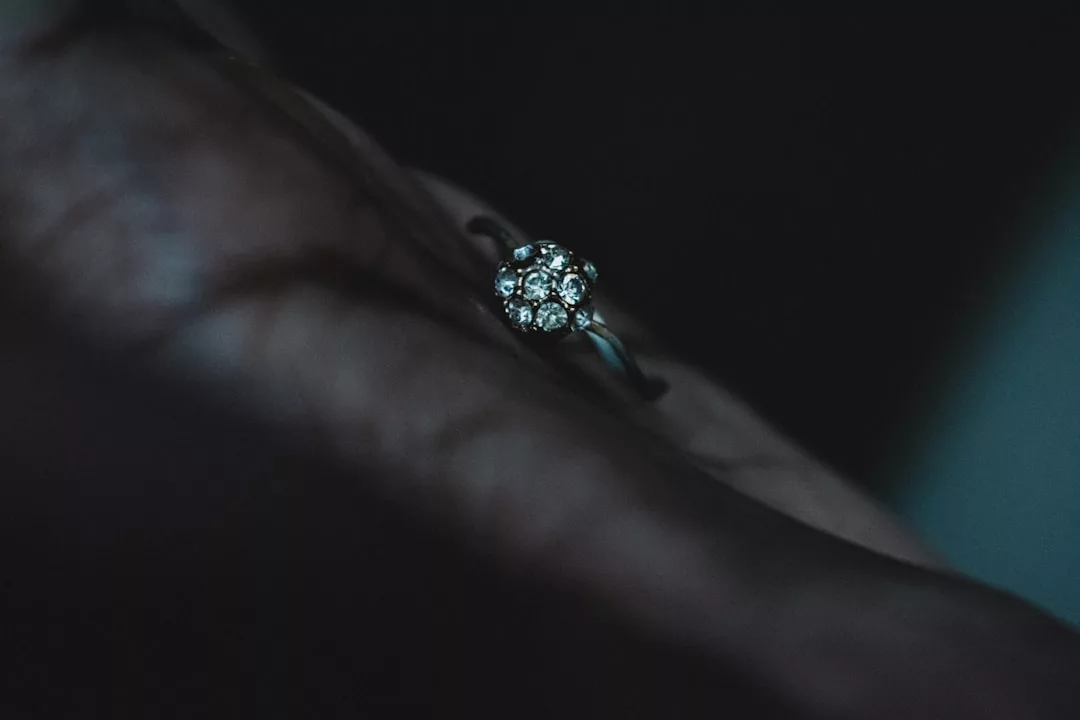 Nahaufnahme einer Hand, die einen GLAMESiA-Silberring trägt, der mit einer Gruppe kleiner, runder Diamanten verziert ist, die in einer zarten Blütenform angeordnet sind.