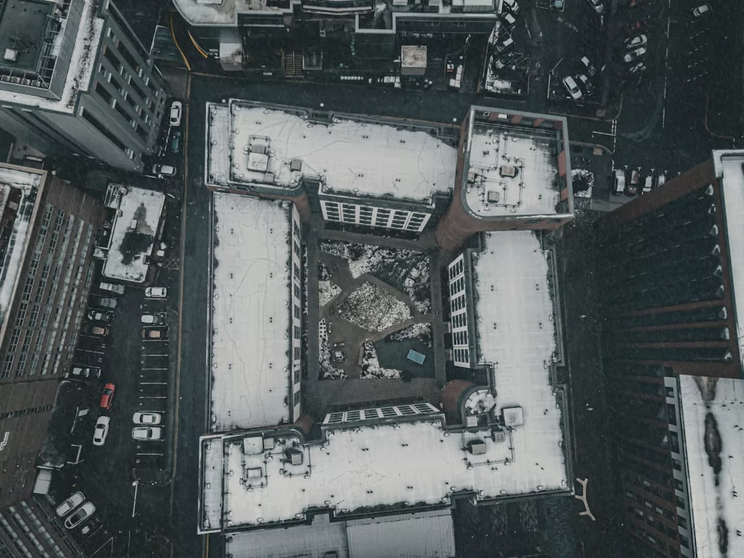 Luftaufnahme des GLAMESiEin schneebedecktes, U-förmiges Gebäude mit einem zentralen Innenhof, umgeben von geparkten Autos und Stadtstraßen.