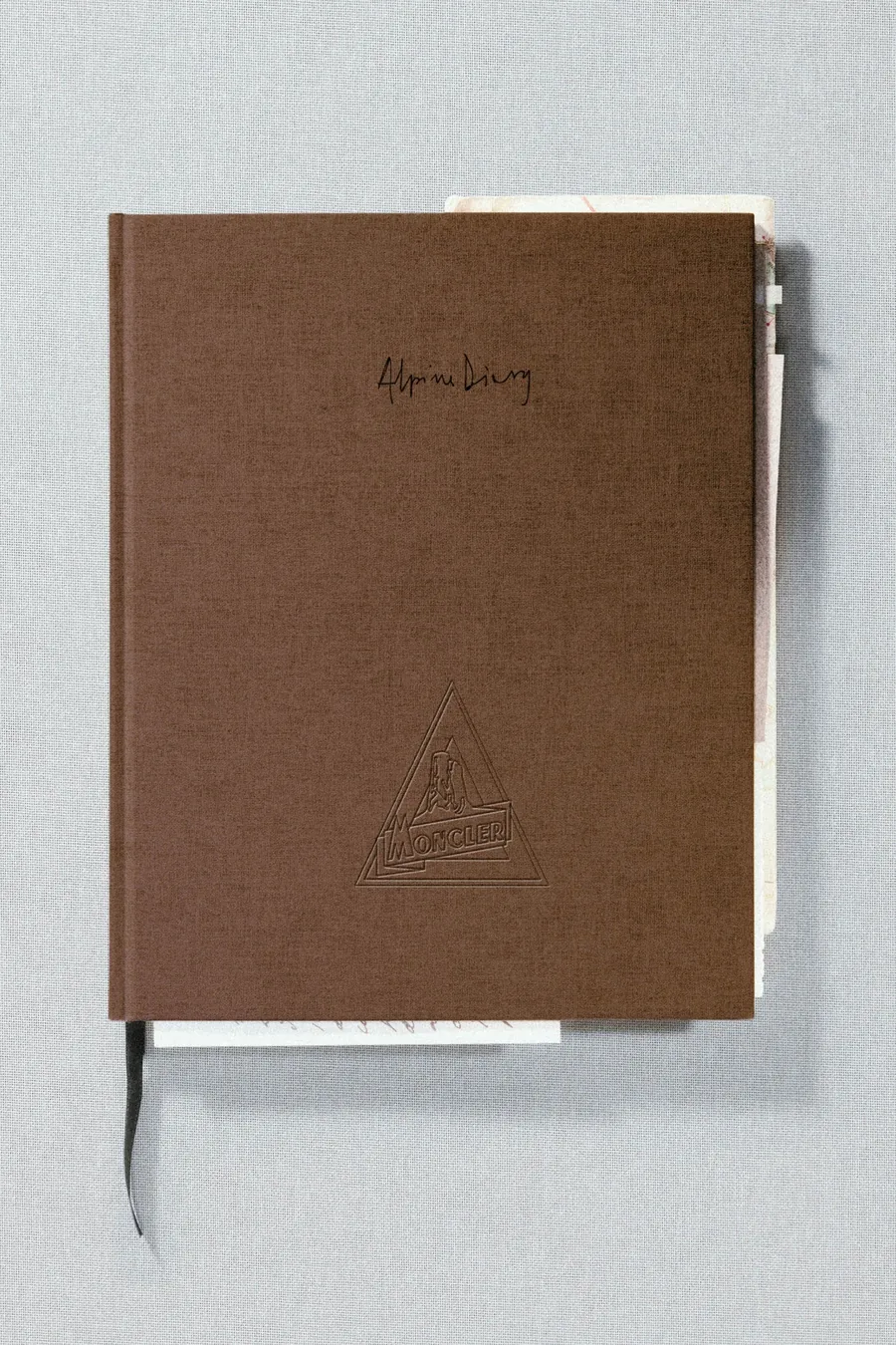 Moncler Alpine Diary: Buch mit braunem Leineneinband und eingeprägtem Bergmotiv