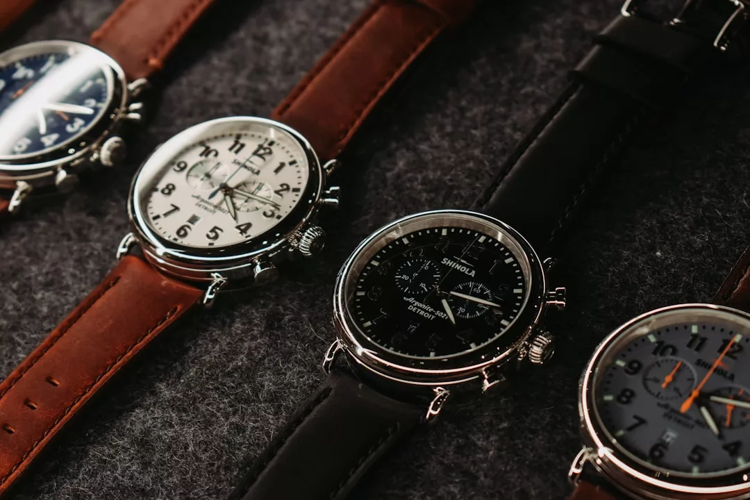 Vier analoge GLAMESiA-Armbanduhren mit Lederbändern sind in einer Reihe auf einer dunklen Filzoberfläche ausgestellt.