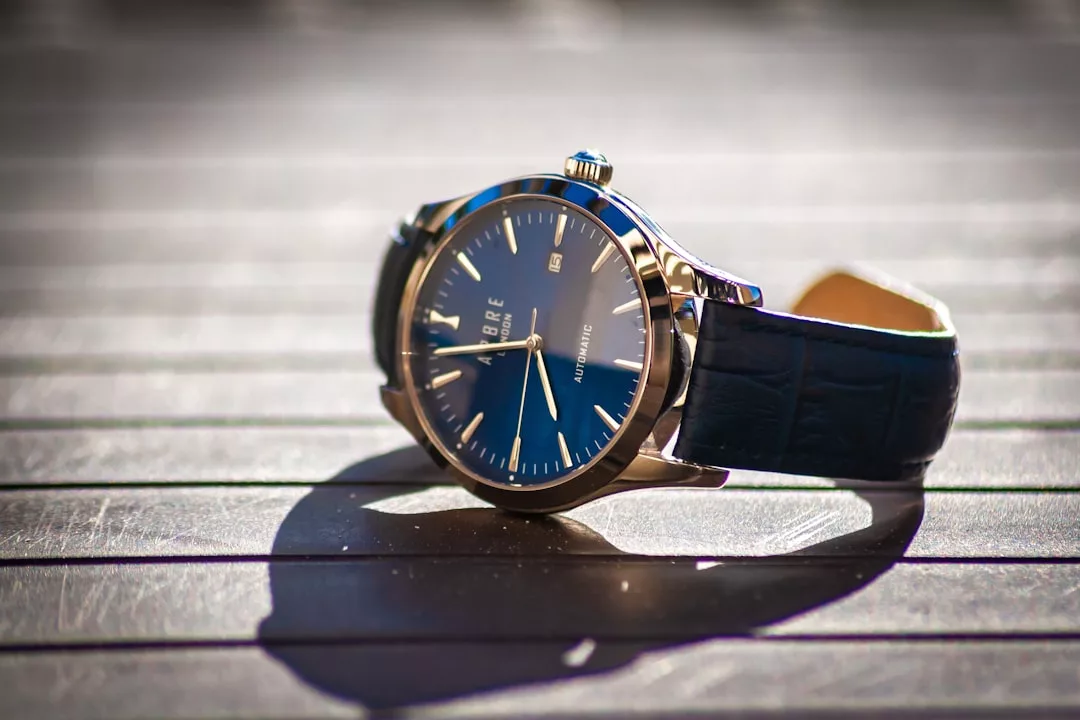 Eine GLAMESiA-Armbanduhr mit blauem Ziffernblatt und dunklem Lederarmband liegt auf einer hölzernen Fläche und wirft im Sonnenlicht einen deutlichen Schatten.