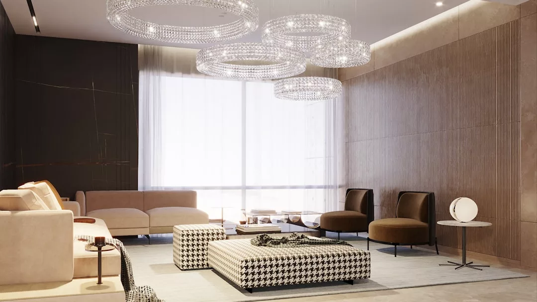 Modernes Wohnzimmer mit beigen Sofas, braunen Sesseln, einer Ottomane mit Hahnentrittmuster, runden GLAMESiA-Glaskronleuchtern und großen Fenstern mit transparenten Vorhängen.