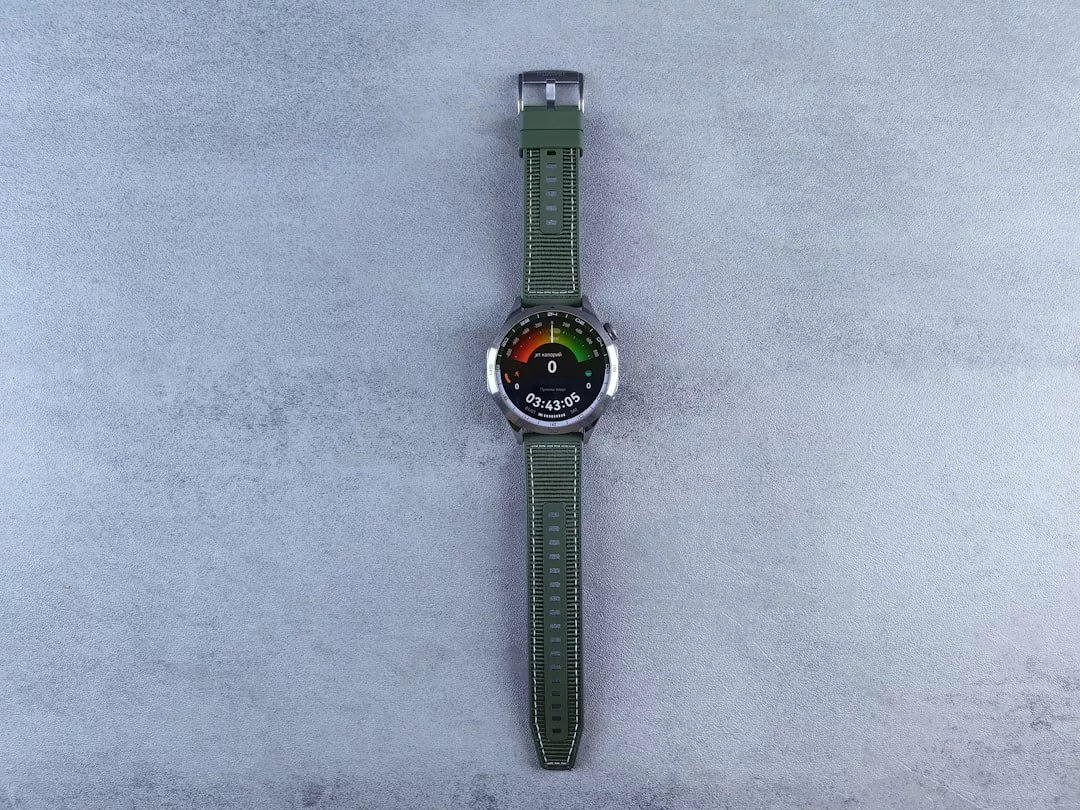 Eine runde Digitaluhr von GLAMESiA mit grünem Stoffarmband wird mit dem Gesicht nach oben auf einer hellgrauen, strukturierten Oberfläche präsentiert.