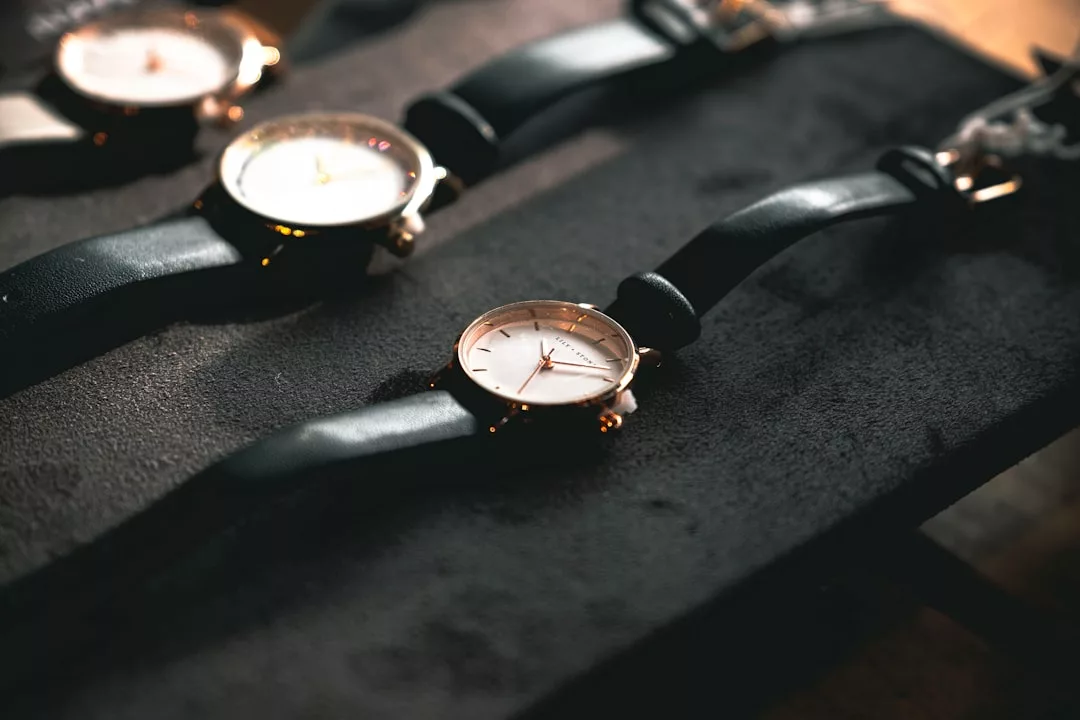 Drei GLAMESiA-Armbanduhren mit schwarzen Lederarmbändern und weißen Zifferblättern werden auf einer dunklen Fläche bei gedämpftem Licht präsentiert.