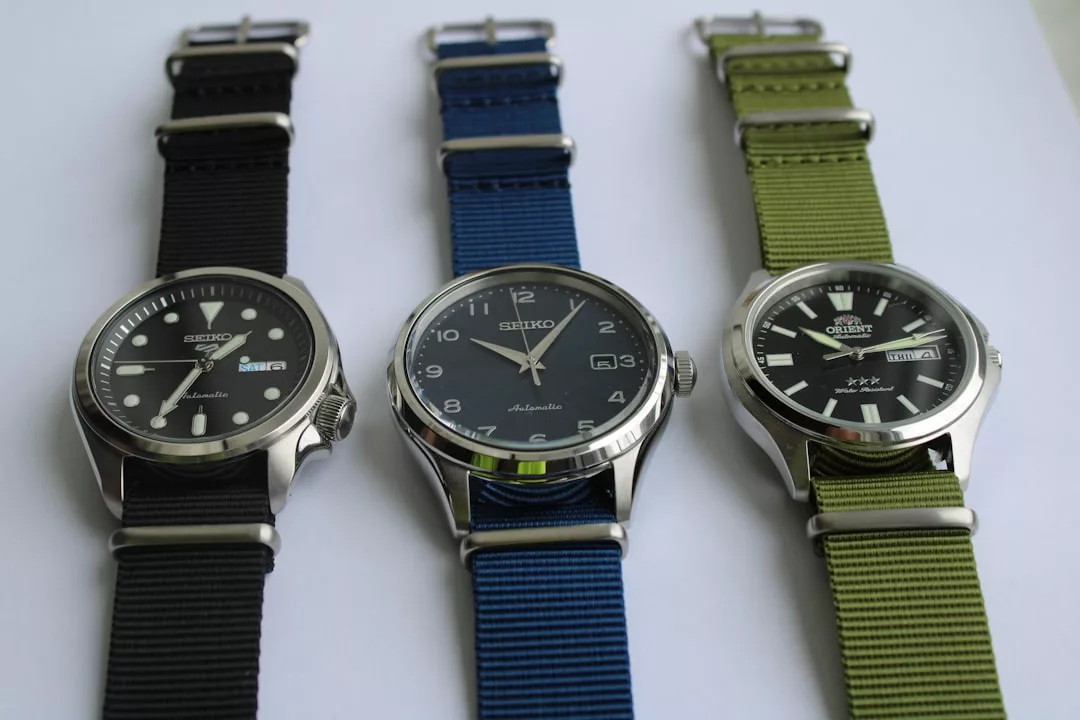 Drei GLAMESiA-Armbanduhren mit schwarzen, blauen und grünen Stoffarmbändern sind nebeneinander auf einer weißen Fläche angeordnet.