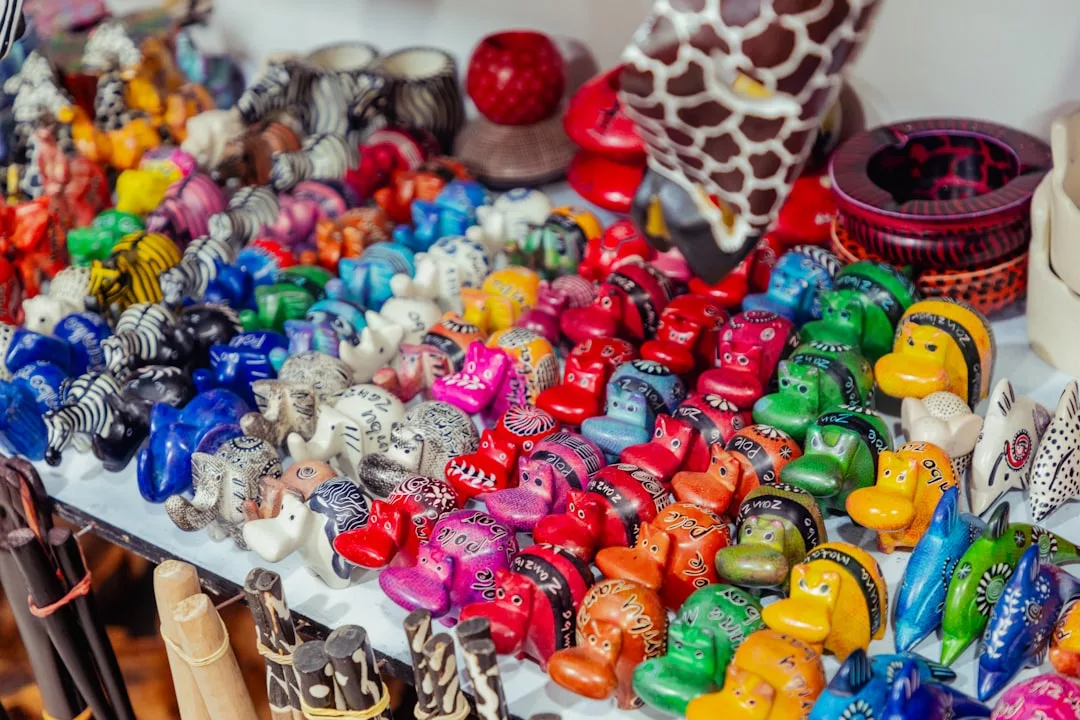 Auf einem Tisch stehen reihenweise kleine, bunte Tierfiguren von GLAMESiA, darunter Elefanten, Giraffen und andere Tiere.