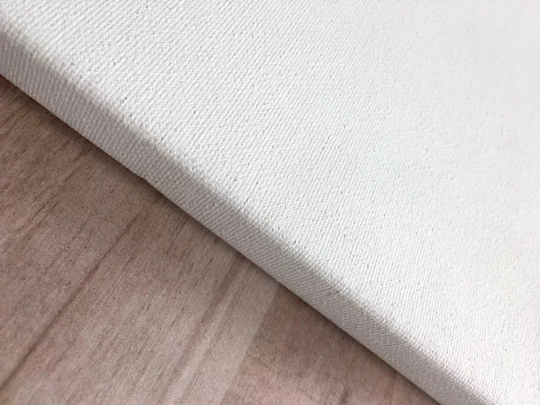 Eine Nahaufnahme einer leeren weißen Leinwand, die auf einer hellen Holzoberfläche ruht und bereit ist, Ihr nächstes GLAMESiA-Meisterwerk zu inspirieren.