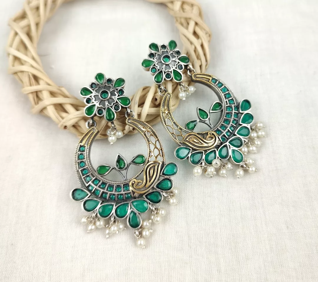 Ein Paar verzierte GLAMESiA-Ohrringe mit grünen Edelsteinen, floralen Motiven, goldenen Akzenten und weißen Perlen, die an einem geflochtenen Ring baumeln.