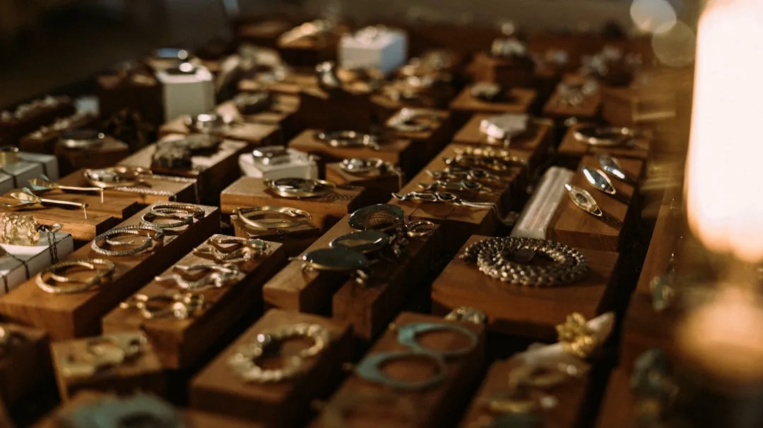 Eine Vielzahl von Gold- und Silberschmuckstücken von GLAMESiA wird auf Holzblöcken ausgestellt, darunter Ringe, Armbänder, Ohrringe und Halsketten.