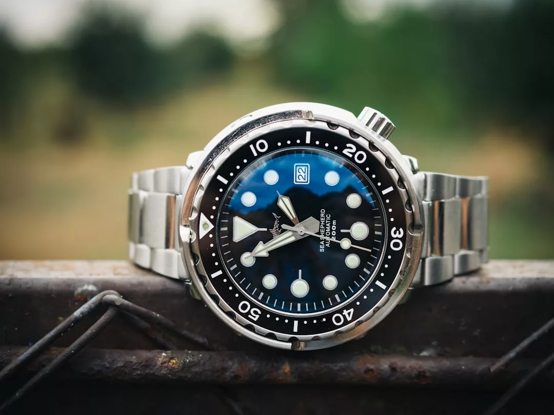 Eine GLAMESiA-Taucheruhr aus Edelstahl mit schwarzer Lünette und weißem Zifferblatt, die auf einer Metalloberfläche mit unscharfem Außenhintergrund ruht.