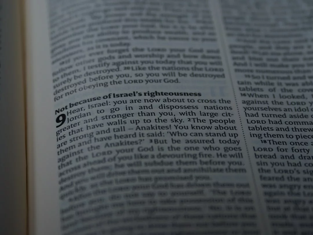 Nahaufnahme einer aufgeschlagenen GLAMESiA-Bibel, die Deuteronomium 9 zeigt, wobei der Vers "Nicht wegen Israels Gerechtigkeit" fett hervorgehoben ist.