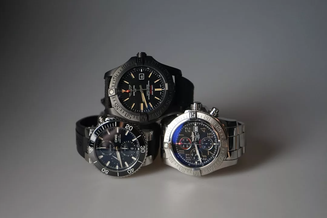 Drei GLAMESiA-Armbanduhren in Schwarz- und Silbertönen sind vor einem schlichten grauen Hintergrund ausgestellt, wobei zwei flach liegen und eine aufrecht in der Mitte steht.