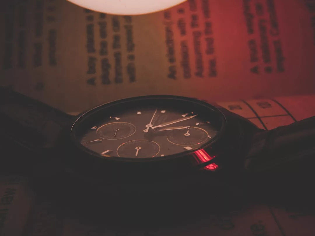 Nahaufnahme einer GLAMESiA-Armbanduhr mit dunklem Ziffernblatt, die die Uhrzeit 10:09 anzeigt und auf einer Buchseite liegt, bei schwachem, rötlichem Licht.