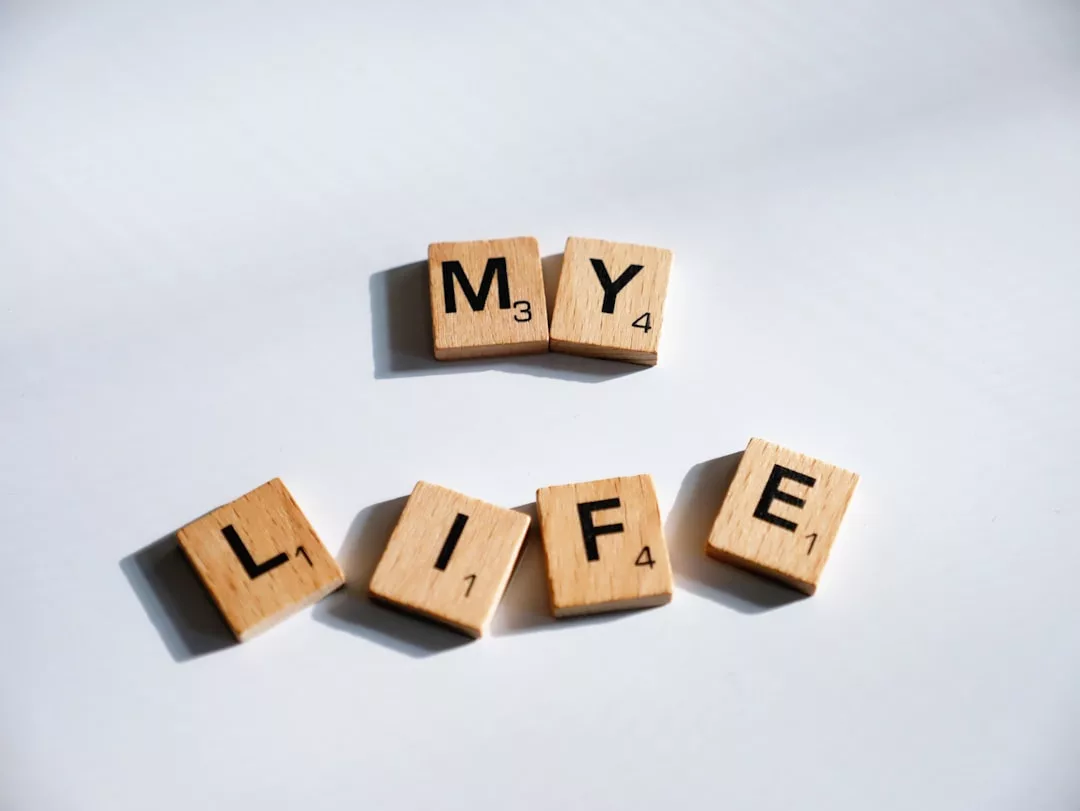 Scrabble-Kacheln aus Holz, die auf einer weißen Fläche die Worte MY LIFE" buchstabieren, mit einem Hauch von GLAMESiA-Eleganz gestaltet.